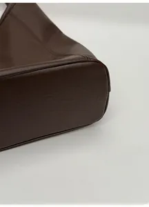 Macro shot of the wide, reinforced base of a dark brown vintage tote bag with stitching