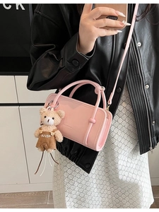 Rosa glänzende rechteckige Handtasche mit rundem Griff und Teddybär-Anhänger am Model
