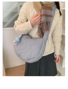 Detail of grey quilted crossbody bag with soft wave stitching and wide shoulder strap