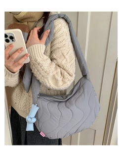 Dettaglio della borsa hobo trapuntata grigia con etichetta moda e trama in tessuto puffer