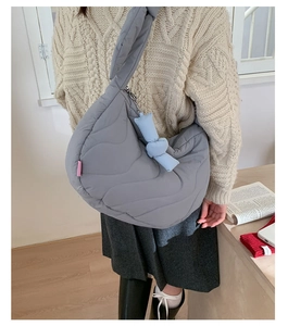 Detail of grey quilted crescent bag with wavy stitching and soft blue knot charm decor