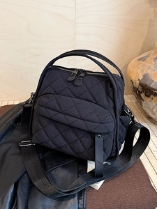 Black quilted crossbody bag with diamond stitch pattern and wide nylon shoulder strap