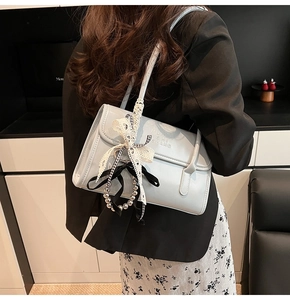 Détail d'un sac à bandoulière en cuir bleu clair avec nœud en dentelle et perles
