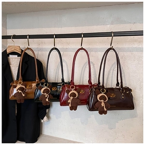 Detail of retro glossy shoulder bags in four colors with knit bear charms on a rack