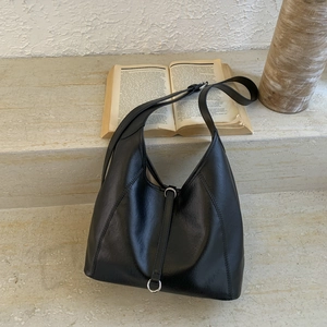Detail of minimalist black faux leather tote featuring a silver metal ring and strap detail