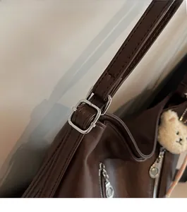 Détail du sac cabas en cuir marron avec ferrures argentées et breloque ours en peluche