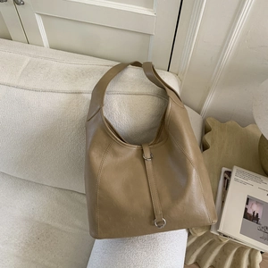 Detail view of khaki hobo bag with silver metal ring on a white fabric sofa