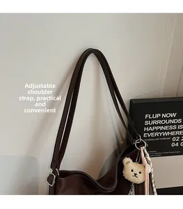 Détail de la bandoulière réglable avec boucle sur le sac fourre-tout marron et peluche