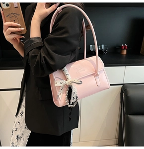 Pink glossy leather shoulder bag with embossed letters and decorative heart ribbon