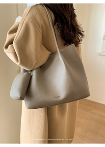Gros plan du sac cabas gris en cuir montrant le grain de litchi et la pochette assortie