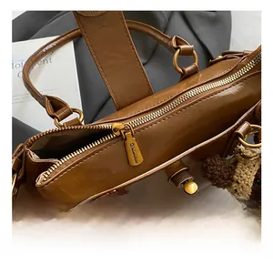Detailed close-up of golden metal zipper and hardware on a brown leather baguette bag