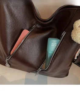 Détail du sac cabas marron foncé montrant les poches zippées et la doublure spacieuse