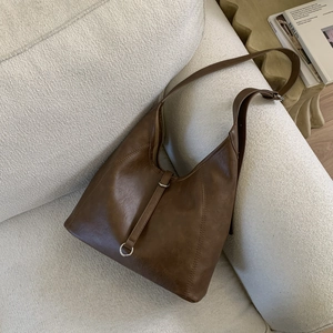Macro detail of dark brown retro leather tote bag with silver ring and vertical strap