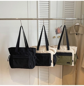 Three multi-color travel tote bags with zippered pockets on a minimalist background