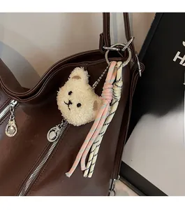 Vue détaillée d'un porte-clés ours en peluche avec glands sur un sac en cuir brun