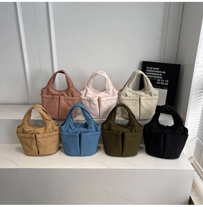 Detail of colorful nylon tote bags with front pockets arranged on white display steps