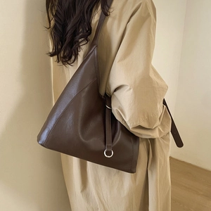 Detail view of large dark brown tote bag with wide strap and silver ring decoration