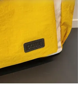 Close-up of the CK&BLI logo on a yellow and white textured fabric travel tote bag