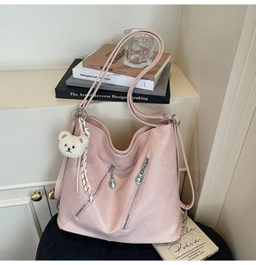 Détail d'un cabas rose en similicuir avec zips métalliques et breloque ourson blanc