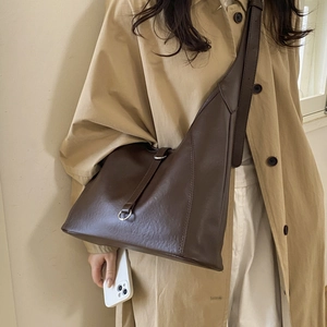 Detailed view of dark brown leather tote with metallic buckle on an adjustable strap