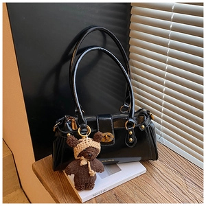 Detail of vintage black leather pillow bag with metal clasp and plush bear charm