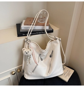 Détail du sac hobo blanc avec fermetures éclair parallèles et breloque ours