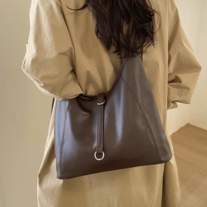 Detail of deep brown tote bag with silver metal ring and vertical strap decoration