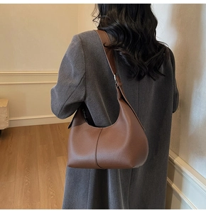 Detailed texture of brown litchi grain leather on a stylish hobo underarm shoulder bag