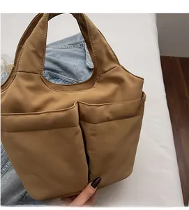 Detail view of khaki large capacity tote bag with dual front pockets and textured fabric