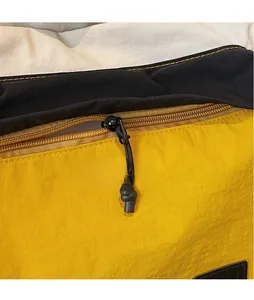 Detail of yellow nylon tote with black long cord zipper puller and reinforced stitching
