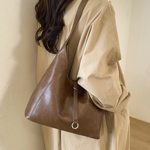Detailed side view of a large dark brown tote bag worn on shoulder by a model