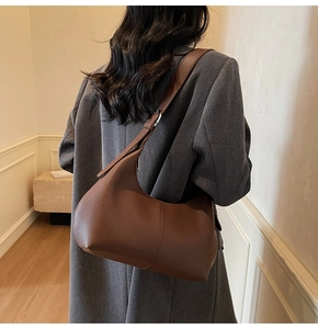 Deep brown litchi pattern leather underarm bag shown with grey textured coat