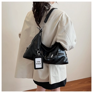 Close-up of black glossy hobo bag with Lazy Breeze tag on a female model shoulder
