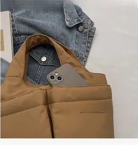 Quilted tote bag detail showing an external pocket holding a smartphone for daily use