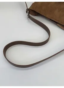 Détail de la bandoulière en cuir réglable et boucle argentée sur sac en daim marron