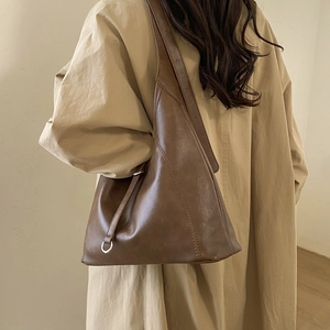 Detail of minimalist coffee brown leather tote bag with silver ring hardware and strap