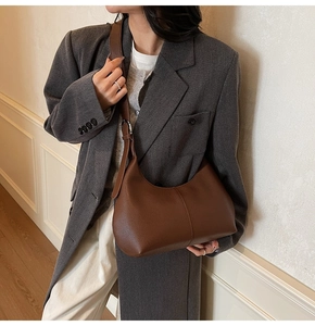 Detail of dark brown lychee leather crescent bag with adjustable strap on a model