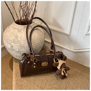 Detail of vintage coffee shoulder bag with polished finish and cute plush bear charm