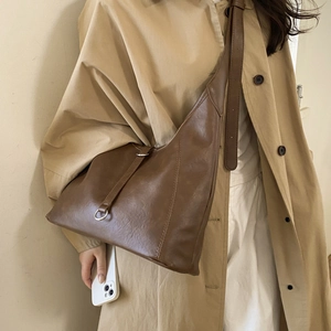 Detailed view of large dark brown PU leather tote bag with silver buckle on a model