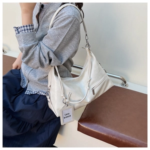 Detailed view of white hobo bag with pleated texture and adjustable strap design