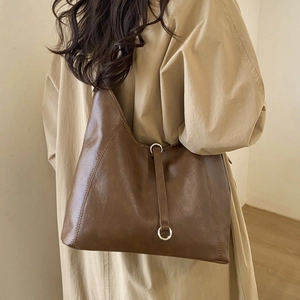 Detail of a large brown faux leather tote bag showing vintage texture and silver hardware