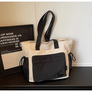 Detail of minimalist nylon tote bag featuring black contrast trim and drawstring side pockets