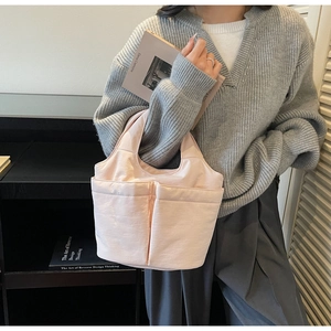 Detail of light pink bucket tote bag with front pockets shown in a modern interior setting
