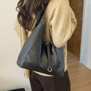 Detail of minimalist black tote bag with diagonal stitching and silver ring buckle