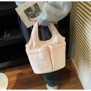 Detail of light pink canvas tote bag with multi-pocket design for organized daily storage