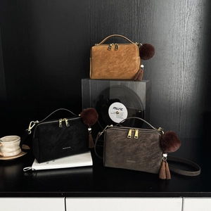 Trois sacs à main en cuir noir, marron et café avec pompons en fourrure et pampilles