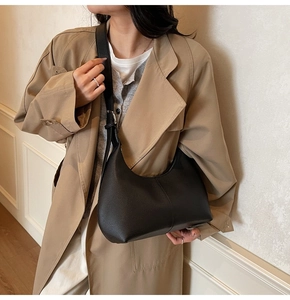 Detail of black lychee grain leather texture on a minimalist crescent underarm bag