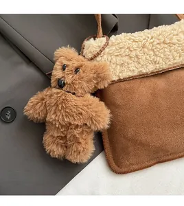 Detalle de un adorable oso de peluche marrón en un bolso de invierno de ante de moda