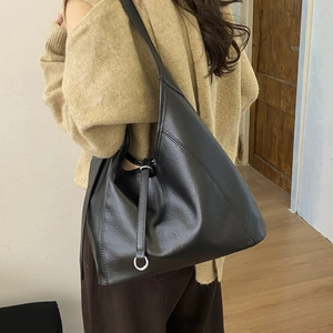 Detail of the side stitching and silver metal ring on the black hobo shoulder bag