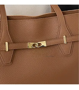 Detail of brown litchi pattern leather tote with golden interlocking metal buckle accent